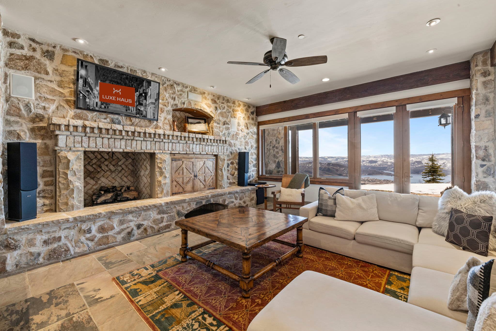 Living space with sectional sofa, stone fireplace, and walk-out patio views